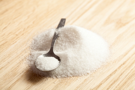 Metal spoon in a pile of white sugar