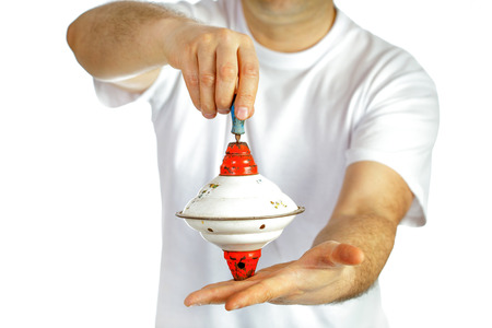 Top toy in hands of a man in white T-shirt