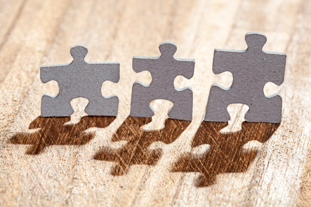 Group of three jigsaw puzzle pieces on a table lit by backlight. Shallow depth of field