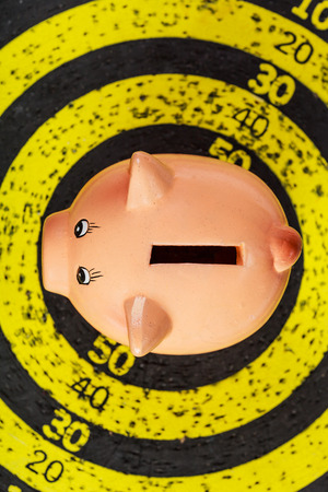 Saving concept: piggy bank on old yellow target boardの写真素材