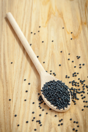 Wooden spoon on board and black lentils. Shallow depth of fieldの写真素材