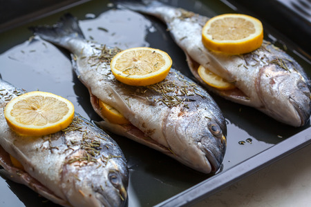 Dorado fish stuffed with lemon slices and rosemary for cooking. Shallow depth of fieldの写真素材