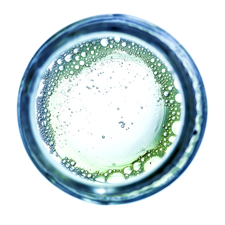 Foam bubbles on round glass frame over white backgroundの写真素材