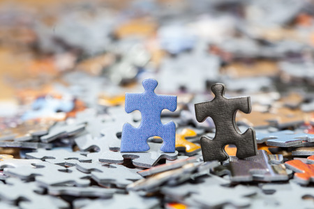 Black and blue puzzle pieces on a pile of jigsaw pieces. Shallow depth of fieldの写真素材