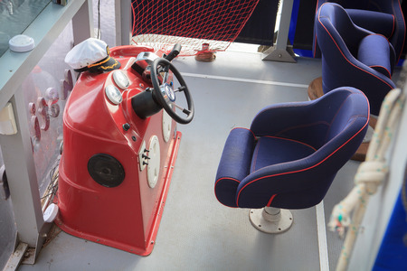 Steering wheel of motor boat and caiptan cap on red instrument panelの写真素材