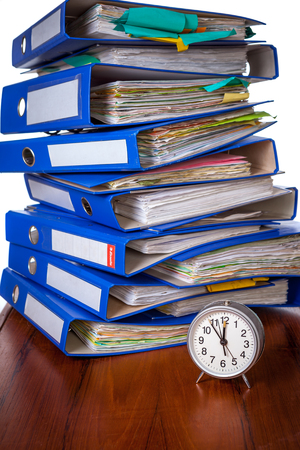 Alarm clock on table against stack of blue office foldersの写真素材