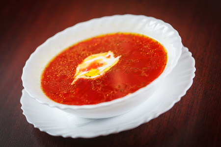 Red beetroot borscht soup in white bowl  on brown tableの写真素材