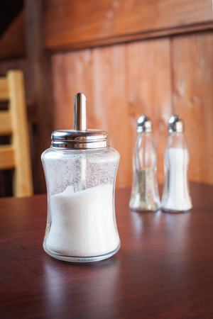 White sugar container on brown table.Salt and pepper shakers on backgroundの写真素材