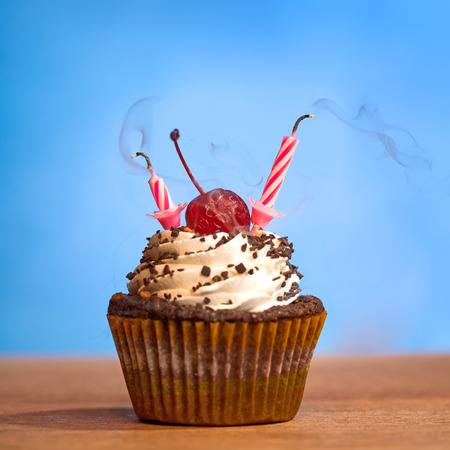 Birthday cupcake with blown out candles over bluye backgroundの写真素材