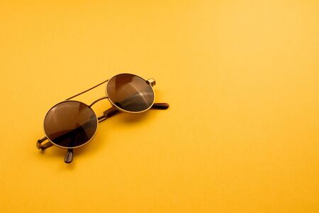 Circle fashion sunglasses on bright yellow background. Summer hipster accessories flat lay with copy space for text or picture. Summer vacation top view. Colorful design for cards. Stock  photo.の写真素材