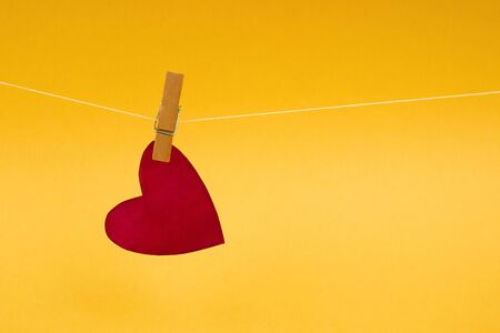 Valentine's Day red heart on clothespin on yellow background. Valentine's day, mother's day and love...
