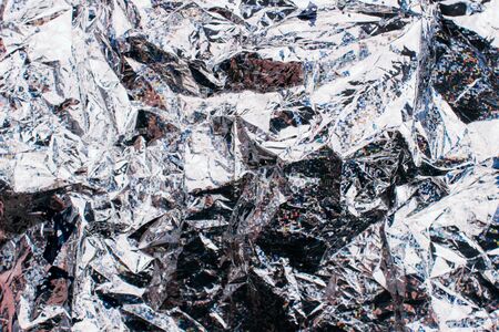 Ð¡rumpled holographic silver foil texture background. Metallic backdrop with scratches and...