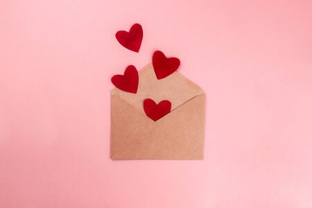 Red hearts flying out from craft paper envelope flat lay on colorful pink background. 8 march,...