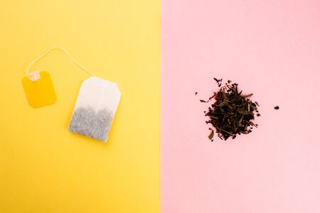 Tea bag and loose leaf tea flat lay on colorful trendy yellow and pink backgrounds. Top view copy...