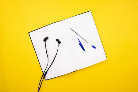 School and office supplies flay lay on colorful yellow background. Notebook, sketchbook, pen, pencil...