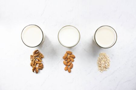 Almond, walnut, oat milk on marble background top view. Nut milk vegan lactose-free, dairy free milk drink. Health diet and nutrition.の写真素材