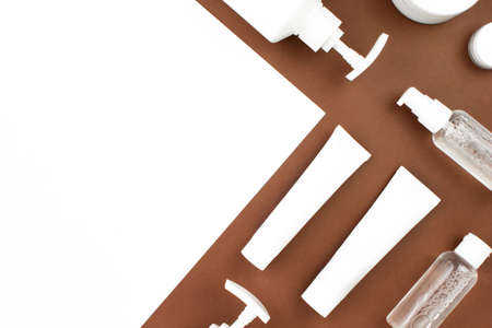 White squeeze tubes, bottles of cream and shampoo, moisturizer flat lay on brown background top view with copy space. Organic, bio, natural cosmetic. Beauty, spa, skincare concept. Stock photoの写真素材