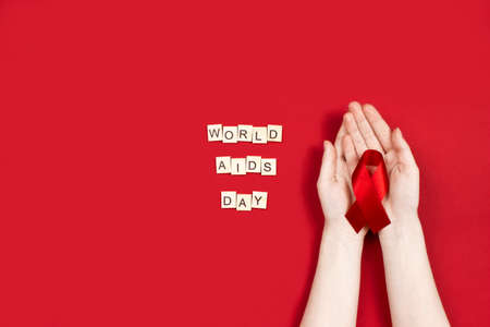 1 december world aids day made of wooden letters and hand holding red ribbon bymbol. AIDS, HIV...