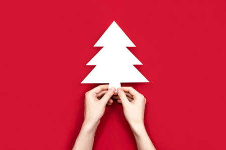Christmas fir tree silhouette cut out of white paper flat lay, copy space. Creative christmas composition top view. Empty blank template. Happy new year, xmas celebration concept. Stock photoの写真素材