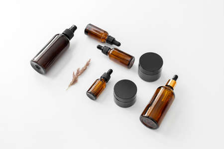 Kit of brown glass bottles and jars flat lay woth pampas grass on white background. Zero waste eco...