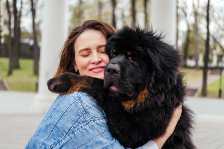 Woman hugging tibetan mastiff dog outdoors. Girl and dog playing in parkの写真素材