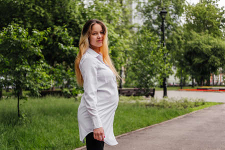 Pregnant young woman walking on street looking at camera outdoors