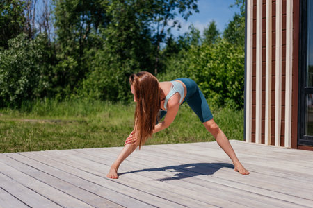 Middle aged woman in sportswear stretching outdoor. Warm-up before yoga training in parkの写真素材
