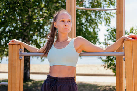 Middle aged woman in sportswear exercising on outdoor fitness equipmentの写真素材