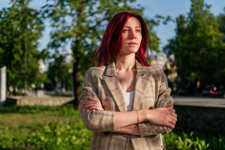 Middle aged businesswoman with red hair standing on street. Confident woman looking away outdoorの写真素材