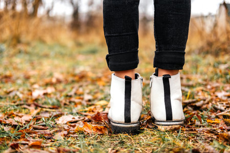 Child in white leather boots standing still outdoors. Autumn hike at forestの写真素材