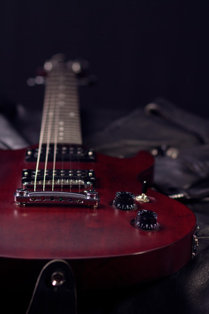 Electric guitar mahogany, lies on the black leather jackets, vertical composition, a stringed...