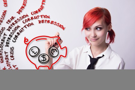 Red-haired girl,the financial crisis, the pig piggy bank, the British pound, the US dollar, saves money, piercings on his face, earrings tunnels, he wrote marker, tie and white shirt, black manicure.の写真素材