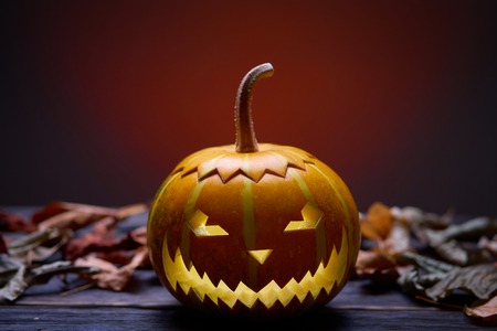 Pumpkin for Halloween, lamp pumpkin, antique wood, celebrating halloween, smiley on a pumpkin, autumn dry leaves, bright background, angry faceの写真素材