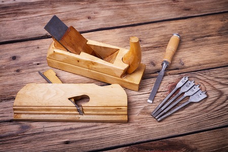 Wooden planer, table from old wood, natural building materials, woodwork and antique hand tools, carrying out carpentry, tool kit for joinery, old wood textureの写真素材