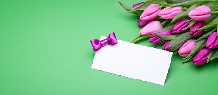 Greeting card, bouquet of beautiful flowers, buds of spring tulips, bow from satin ribbon, the gift set on a green backgroundの写真素材