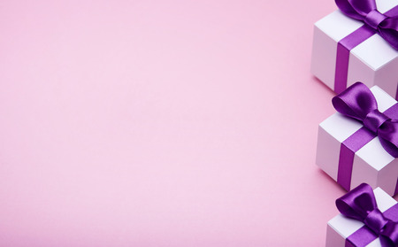 Gifts in a beautiful package, bow from satin ribbon, a few boxes with gifts, attributes festive mood, the gift set on a pink backgroundの写真素材