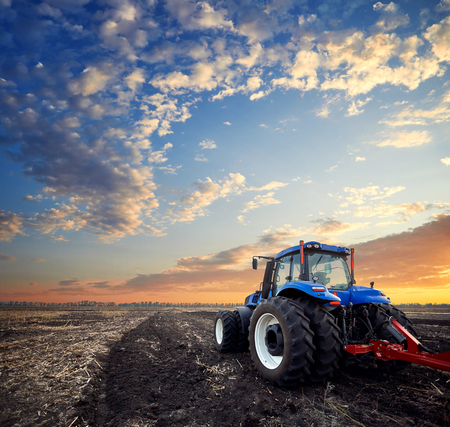 Tractor working on the farm, a modern agricultural transport, a farmer working in the field, fertile land, tractor on a sunset background, cultivation of land, agricultural machineの写真素材