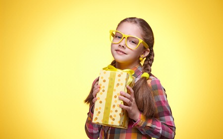 Teenager with a gift, happy smile, children's emotions, girl with glasses, bright checkered shirt, beautiful young lady, portrait of a young girlの写真素材