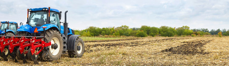 Tractor working on the farm, agrarian industry, a modern agricultural transport, cultivation of fertile land, tractor on cloudy sky background, agricultural machineの写真素材