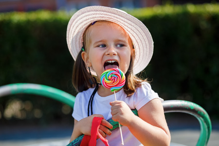 Little girl eating big candy. Shallow depth of field.の写真素材