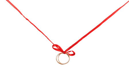 Wedding rings on a red ribbon with a bow. Isolated on white background.の写真素材