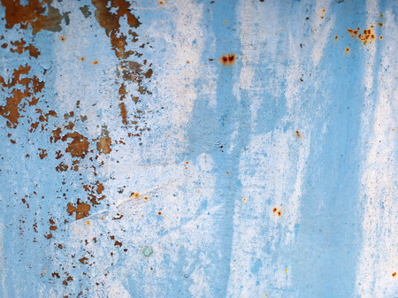Old blue grunge material. Peeling paint and rust stains. Shallow depth of field.