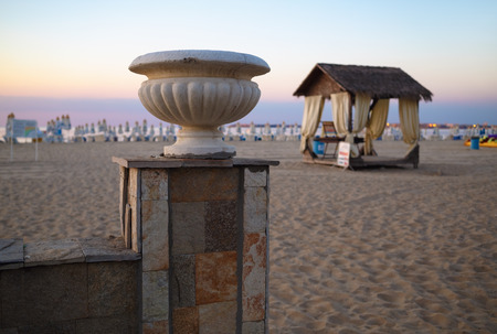 Morning landscape with plaster vase and a canopy on the sandy beach. Shallow depth of field. Focus on the old plaster vase.の写真素材
