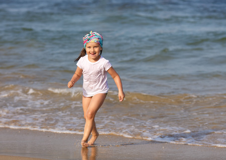 Smiling child with his tongue hanging out in a white t-shirt runs the waterの写真素材