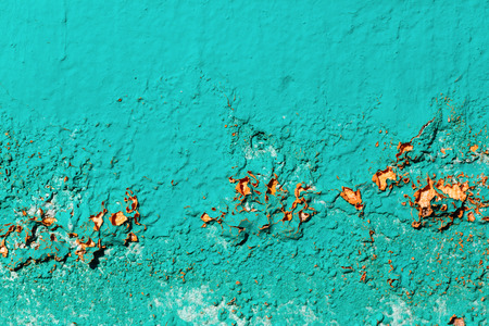 Old wall painted in bright turquoise color. Damaged and cracked paint texture.の写真素材
