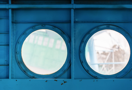 Two metal portholes with bolts on painted blue metal background. Inside view of the old aircraft.の写真素材