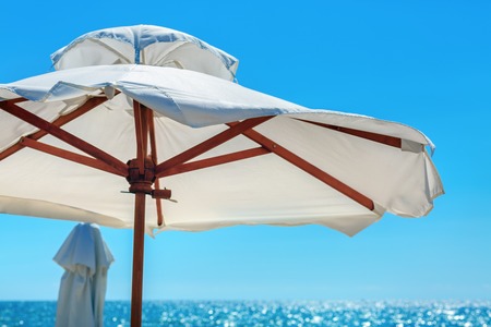 Big white parasol on a background of bright blue sky closeup. Beach umbrella.の写真素材
