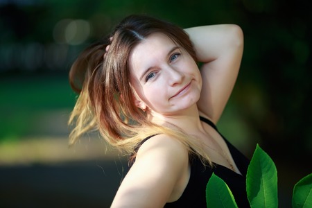 Girl posing outdoors. Close-up portrait of a pretty young woman. Sunny summer day. Shallow depth of field. Selective focus on the model's face.の写真素材