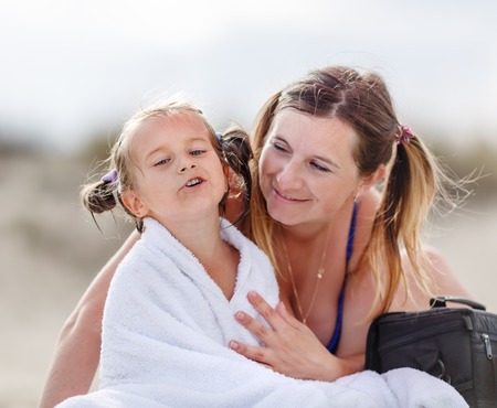 Mom wiped his little daughter with a towel after swimming in the sea. Parental care. Shallow depth of field. Selective focus on child's face.の写真素材