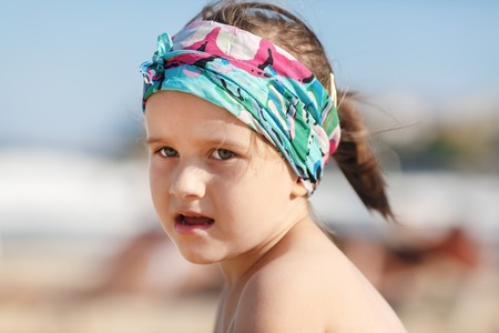 Portrait of a little girl child in a headscarf. Hot sunny summer day. Shallow depth of field. Selective focus.の写真素材